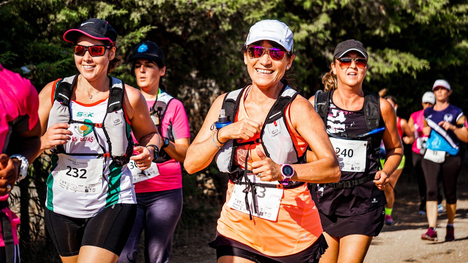 A group of smiling runners moving together on a trail.