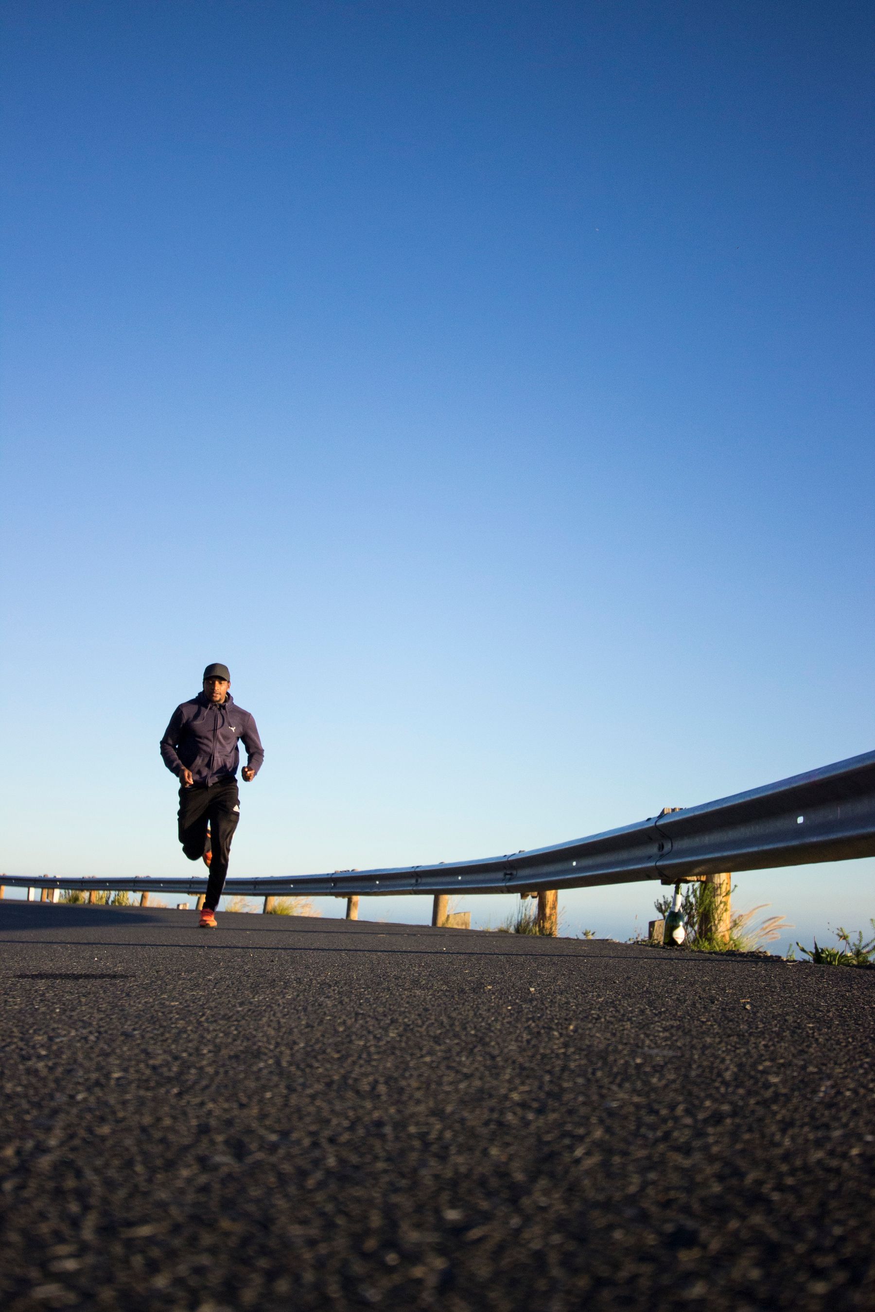 A person running on an open road under a clear sky.