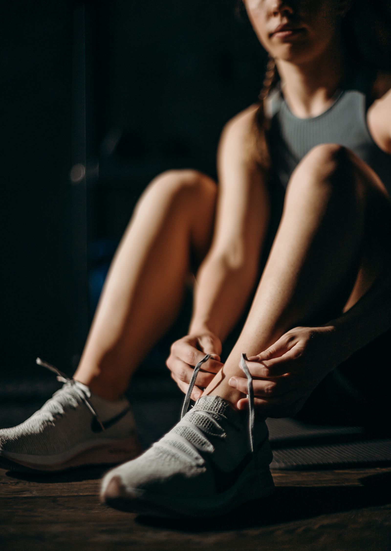 A runner tying a light-colored shoe before heading out.